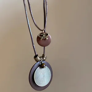 Gros plan d'un collier pendentif en bois de style zen avec spirale métallique