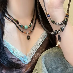 Détail de colliers ethniques superposés avec perles en bois et turquoise sur mannequin