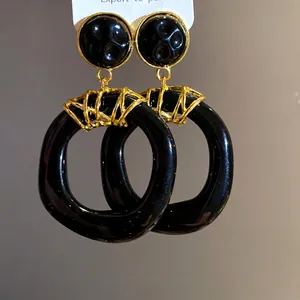 Eleganti orecchini vintage a pendente in resina nera irregolare con dettagli dorati.