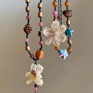 Détail d'un collier bohème en perles de bois avec pendentif fleur tissé à la main
