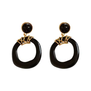 Orecchini a pendente vintage in resina nera irregolare con accenti dorati da donna.
