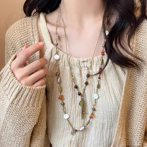 Détail d'un collier bohème multicouche avec perles en bois et glands vintage.