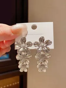 Dettaglio ravvicinato di eleganti orecchini a goccia con fiori color argento e nappe