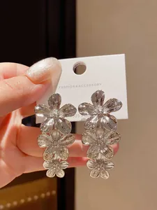 Dettaglio di grandi orecchini a fiore d'argento con perni in argento S925 di tendenza.