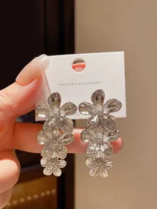 Dettaglio di eleganti orecchini a fiore d'argento lucido con ago in argento S925 per la moda.