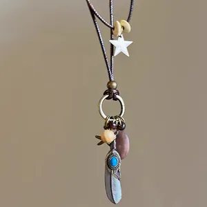 Gros plan détaillé collier bohème ethnique en perles de bois avec plume et pierre bleue