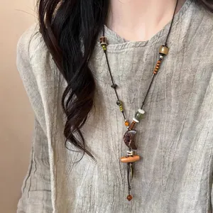 Gros plan d'un collier ethnique en perles de bois avec pendentif lune sur vêtement en lin