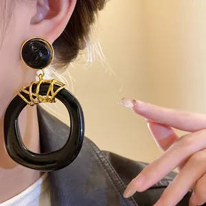 Vista dettagliata di orecchini pendenti in resina nera irregolare in stile vintage con oro