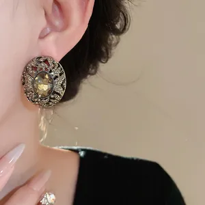 Primo piano di orecchini vintage ovali con strass e pietra centrale ambrata.