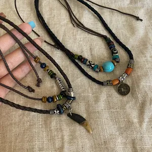 Vue détaillée de colliers bohèmes ethniques avec perles en bois et pendentif dent de loup