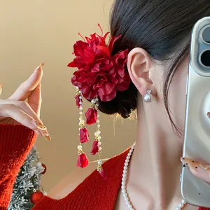 Close-up showing the intricate detail of a red fabric flower hair clip with tassels