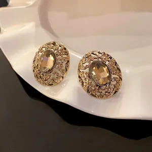 Vista macro di orecchini a perno vintage dorati con strass color champagne scintillanti