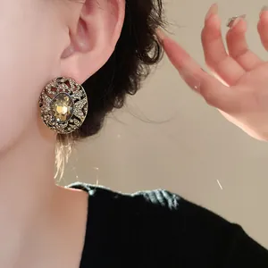 Dettaglio di un orecchino ovale vintage in stile corte con gemma ambrata su modella asiatica