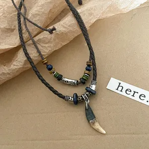 Détail du collier bohème à plusieurs rangs avec pendentif dent de loup et perles.