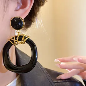 Vista dettagliata di orecchini vintage in resina nera con accenti dorati indossati da una modella