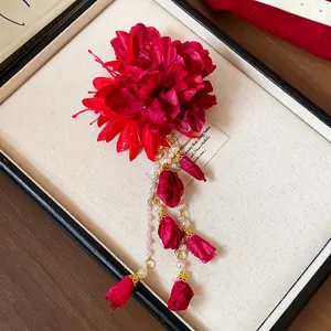 Close-up of handcrafted red fabric flower hair clip with pearl and bud tassels