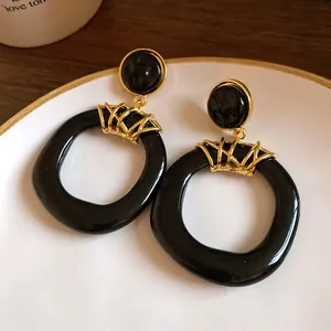 Dettaglio di orecchini vintage in resina nera con eleganti accenti in metallo dorato