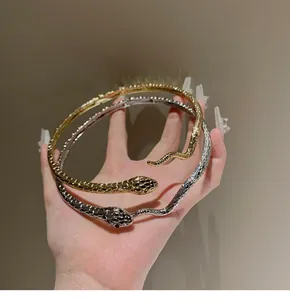 Primo piano di girocolli a serpente in oro e argento con trama a scaglie dettagliata.