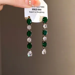 Détail macro de boucles d'oreilles pendantes en zircon vert et blanc