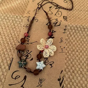 Gros plan d'un collier Zen ethnique avec perles en bois et fleur tissée à la main.