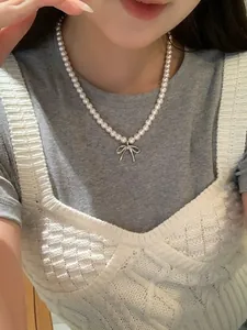 Elegant pearl necklace with silver bow pendant shown on a model in a lifestyle setting