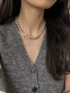 Close-up of an elegant silver-tone bow beaded choker necklace on a grey cardigan