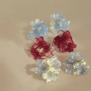 Close-up of elegant resin flower stud earrings with pearlescent texture and silver needles.