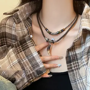 Détail d'un collier bohème vintage avec des perles de bois et un pendentif en corne.