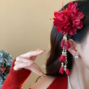 Detailed view of an elegant red fabric flower hair clip with pearl tassel worn by model.