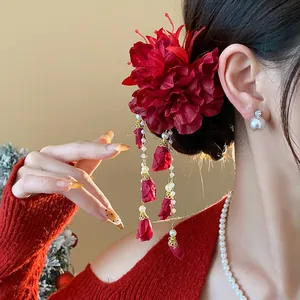 Close-up of a red fabric flower hair clip with elegant pearl tassels on model.
