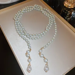 Macro view of long multi-layer pearl necklace with elegant teardrop pendants.