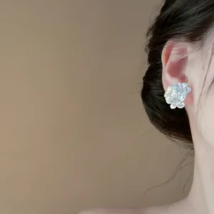 Detailed close-up of elegant pearly white resin flower earring worn on an ear