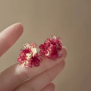 Detailed close-up shot of elegant red resin flower stud earrings with silver needles