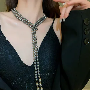 Close-up detail of a long double-strand grey pearl necklace with vintage gold end caps