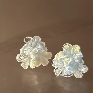 Macro shot of iridescent resin flower stud earrings with shimmering blue petals