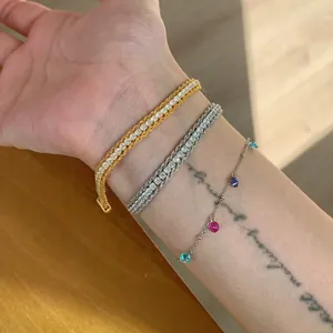 Elegant zircon bracelet set with gold and silver tennis chains on wrist.