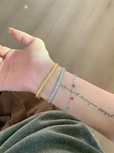 Detailed view showing three stacked zircon bracelets in gold and silver on a woman's wrist