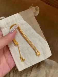 Close-up macro shot of the elegant gold-plated zircon bracelet placed on a cream linen pouch