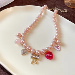 Detailed view of a pink pearl necklace with rhinestone heart and bow charms on a plate