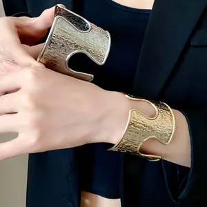 Primo piano della trama martellata e del design a intaglio dei bracciali oro e argento.