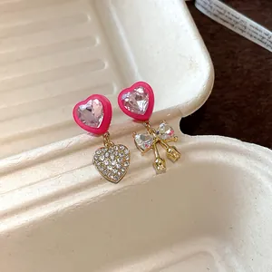 Close-up detail of asymmetrical pink heart earrings featuring bow and tulip charms
