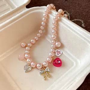 Close-up detail of a sweet pink pearl necklace with heart and bow charms in a tray