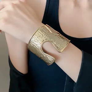 Primo piano di un bracciale rigido dorato martellato con un grande intaglio minimal