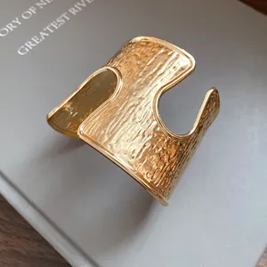 Primo piano della trama dorata stropicciata e del design traforato del bracciale rigido