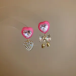 Asymmetrical pink heart and crystal bow drop earrings with sparkling rhinestone detail.