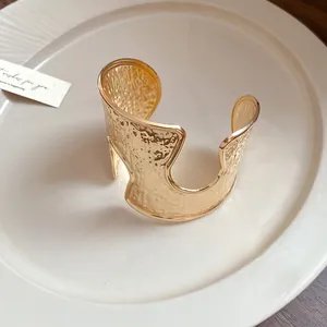 Vista macro dettagliata di un bracciale rigido dorato martellato su un piatto di ceramica