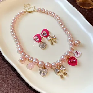Close-up of sweet pink pearl necklace and heart earrings set on a ceramic tray.