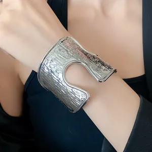 Dettaglio ravvicinato di un bracciale rigido martellato argento con un design a cerchio ritagliato.