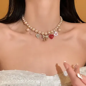 Close-up view of elegant pink pearl necklace with heart and bow charms on a model