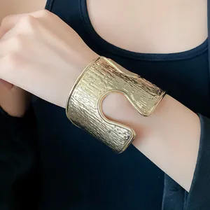 Vista dettagliata di un bracciale a polsino dorato testurizzato con design a giorno